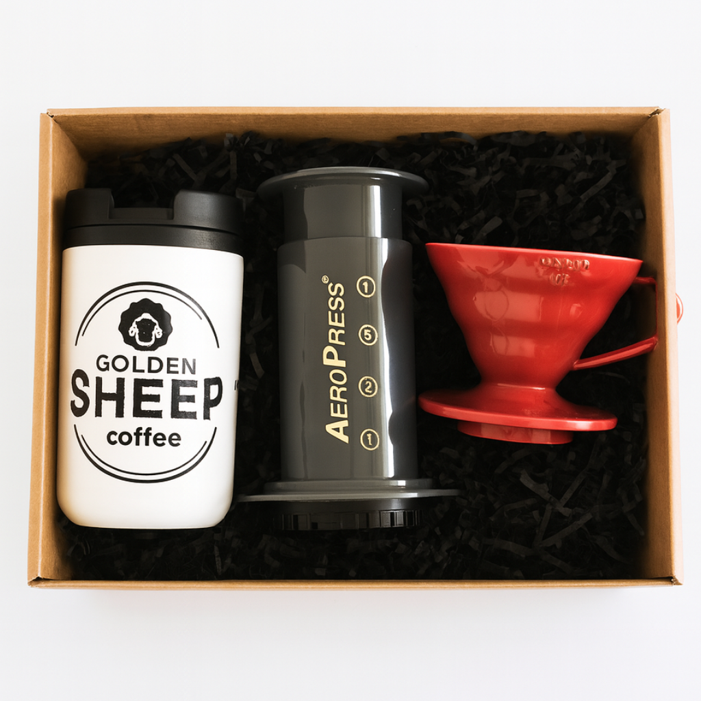 Coffee-making set with Golden Sheep coffee tumbler, Aeropress, and red pour-over cone in a box.