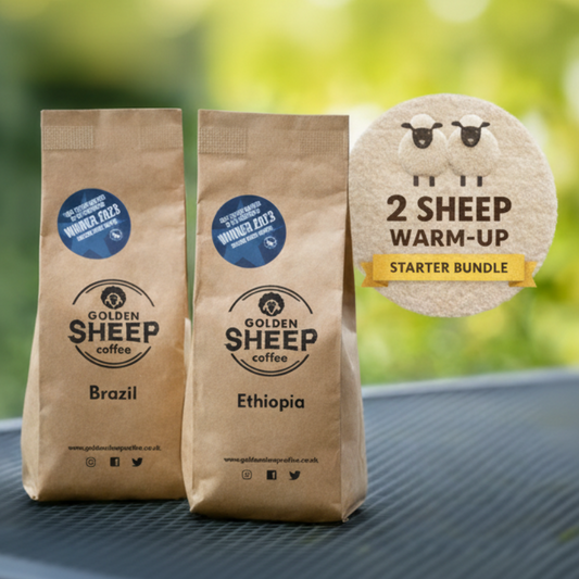 Two brown coffee bags labeled 'Golden Sheep Coffee' with a promotional sign in the background.