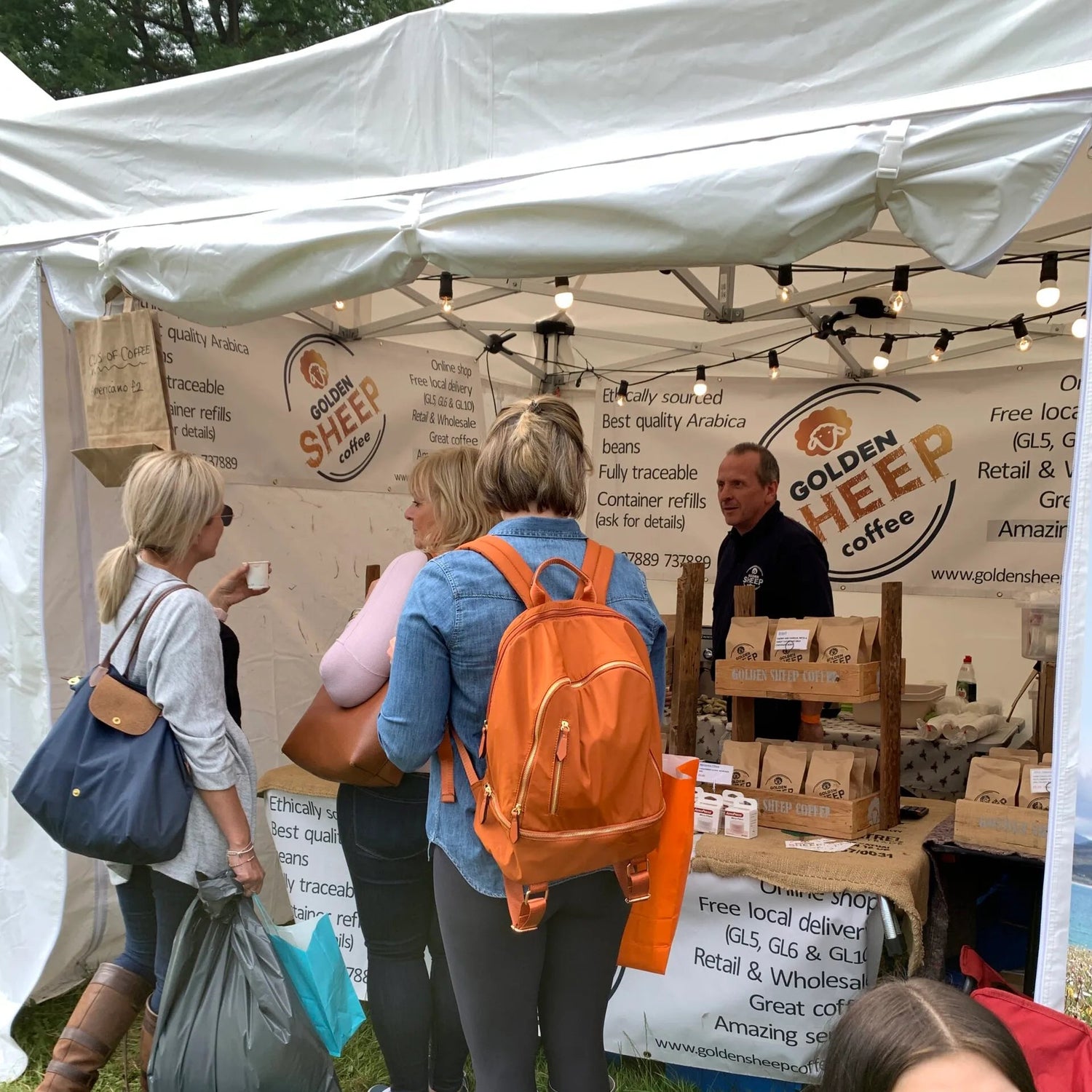People at a Golden Sheep Coffee booth at an outdoor event