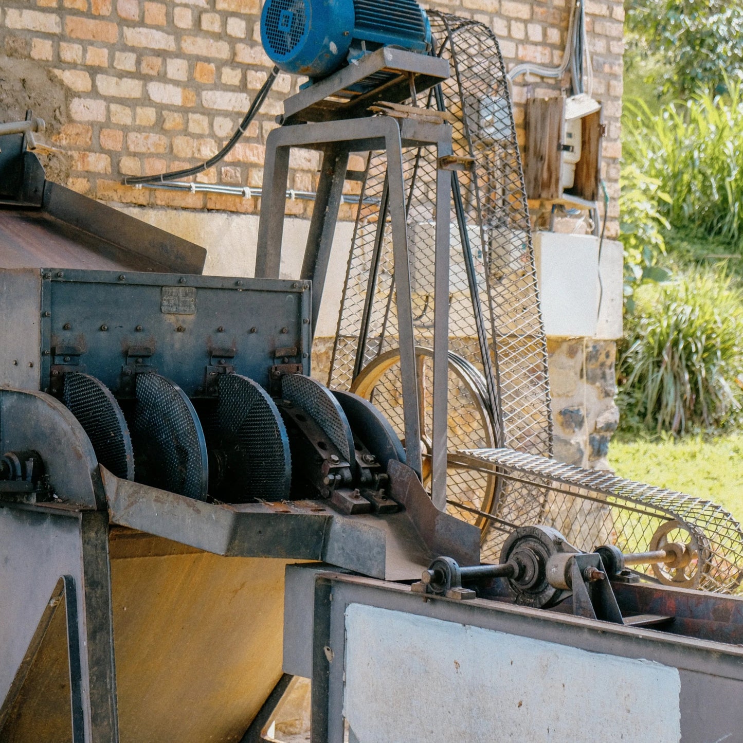 Industrial machine with a stone wall and greenery in the background