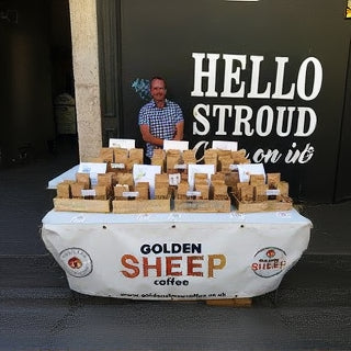 Michael standing behind a table with boxes of Golden Sheep coffee at a 'Hello Stroud' event.