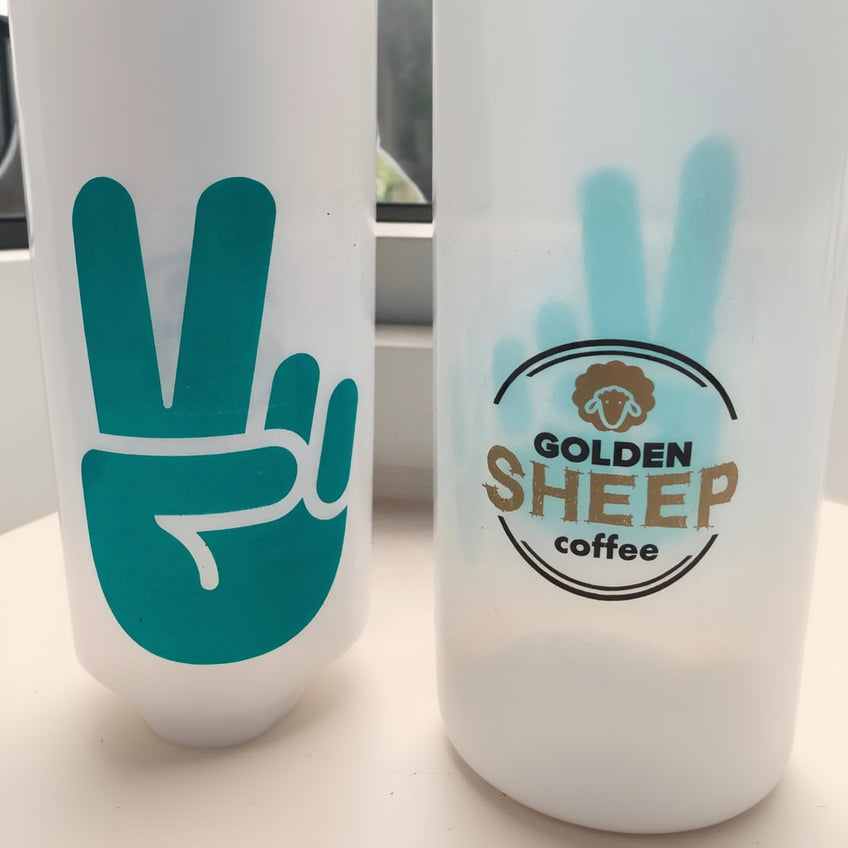 Two water bottles, one with a peace sign design and the other with 'Golden Sheep Coffee' branding.