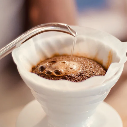 Coffee being poured into a white coffee filter with a blurred background