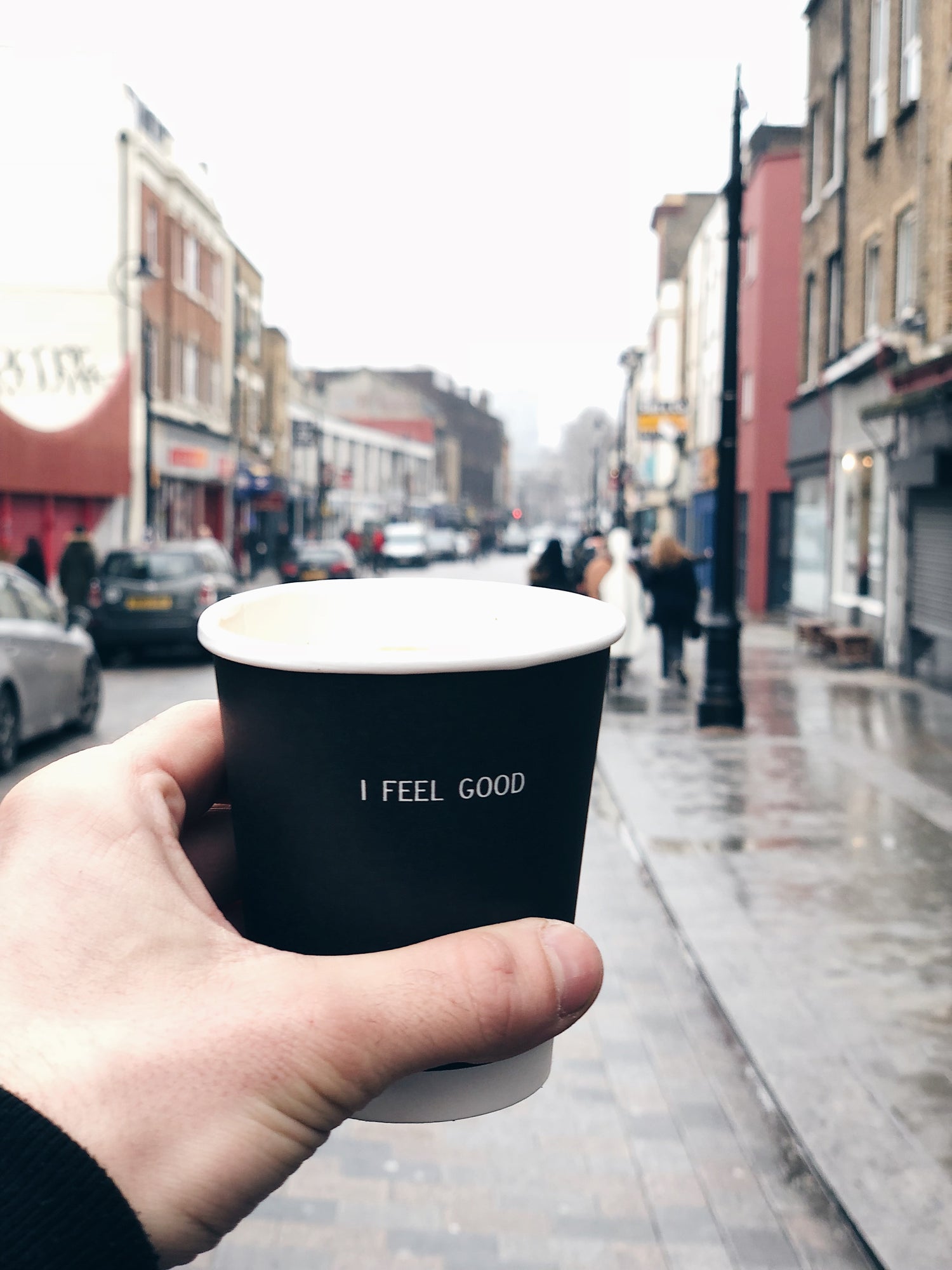 coffee cup held up with stroud shops in the background